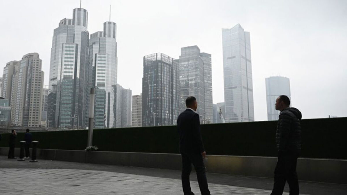Two men chat outside office buildings in the central business district in Beijing on March 4, 2026. PHOTO: AFP