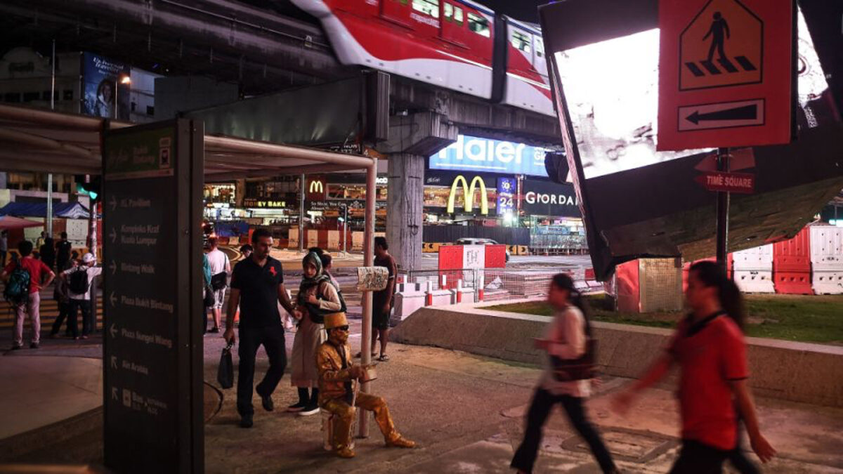 This picture taken September 21, 2016 shows Malaysian street performer known as 'Goldman' (C) posing on a street in the popular Bukit Bintang tourist spot in Kuala Lumpur. PHOTO: AFP