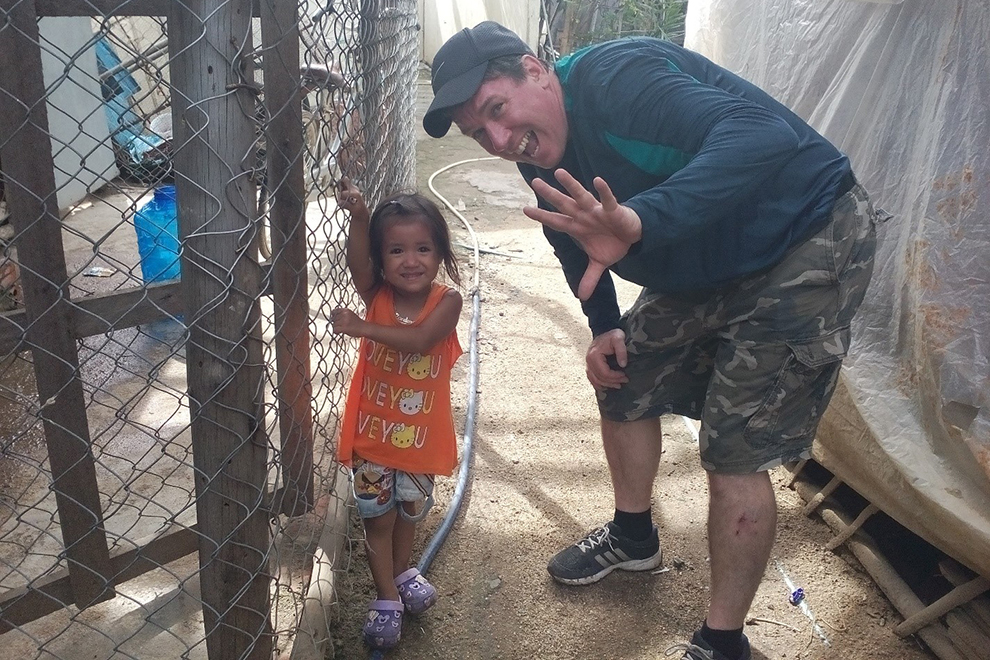 Darin Wyman poses for a picture with a young resident of Stung Meanchey, who now has access to healthy, clean water. WOLPC