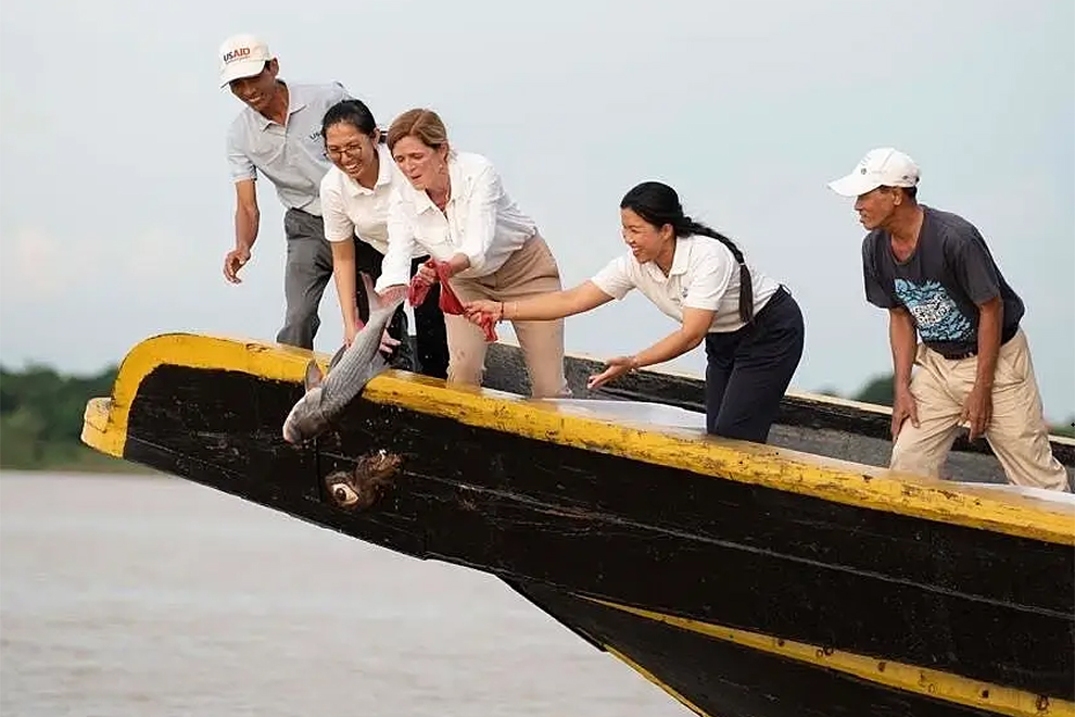 Travelling by boat down the Tonle Sap River to its confluence with the Mekong, Power releases endangered fish into the water. USAID