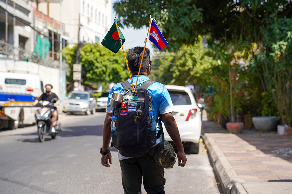 The flags of Bangladesh and Cambodia adorn Shanto's backpack as he walks through Phnom Penh. Leap Tepitou