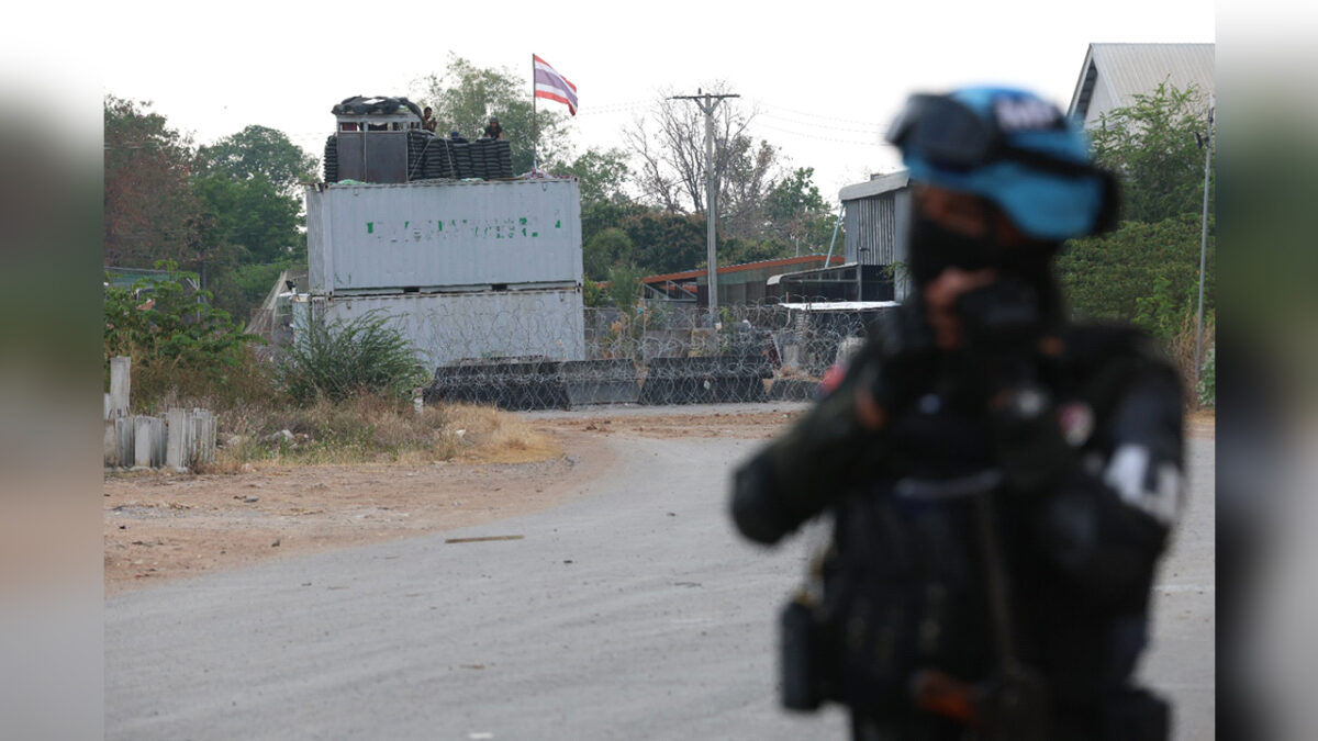 A Cambodian soldier (foreground) is observed by Thai military personnel from atop the shipping container barricades they have placed on occupied Cambodian territory in Banteay Meanchey province. Supplied