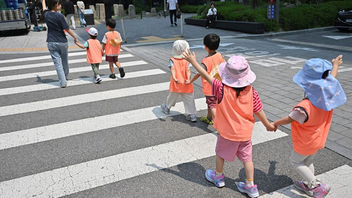 Children cross a street in Seoul on May 30, 2025. PHOTO: AFP